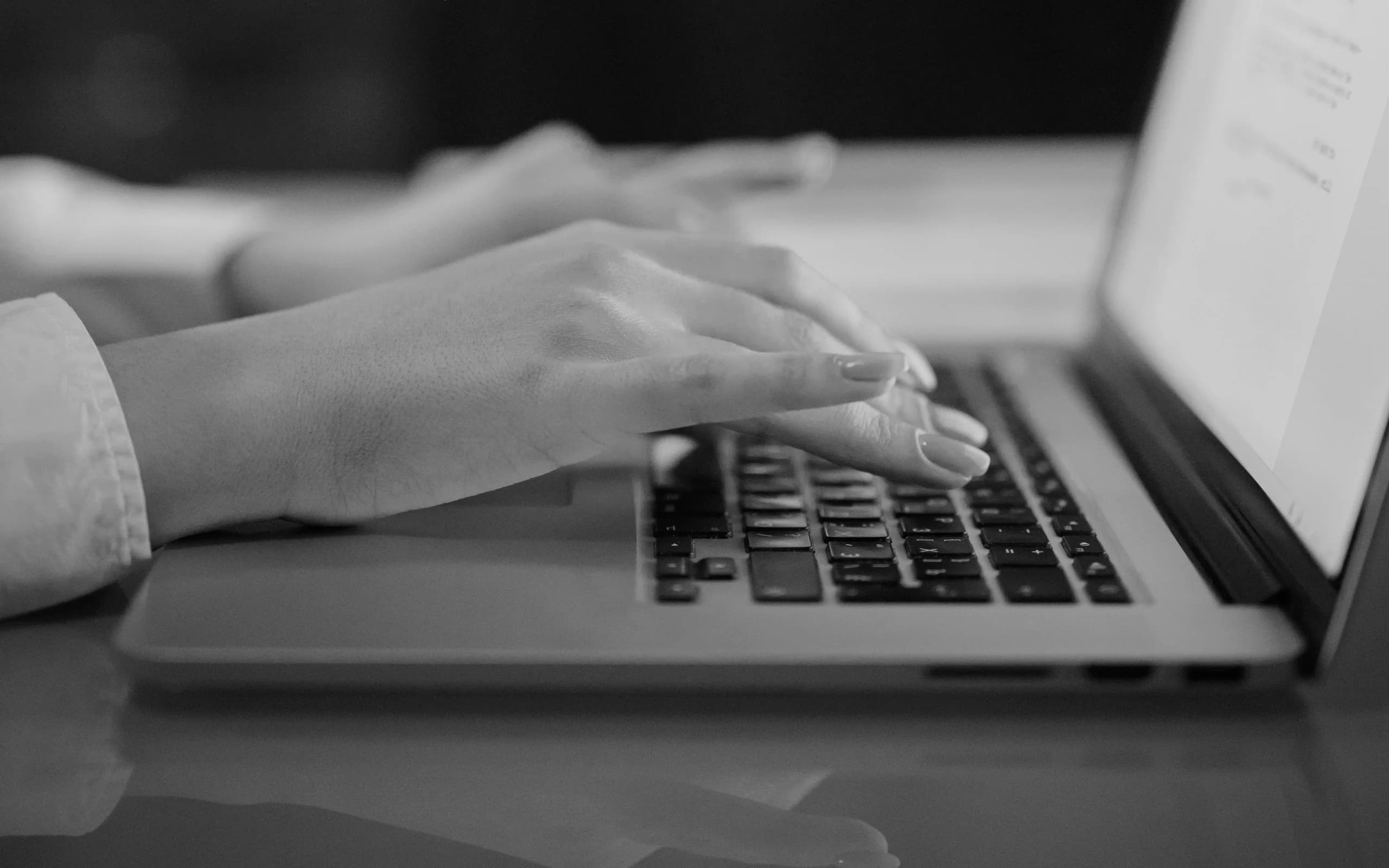 Hands typing beside a softly blurred laptop screen